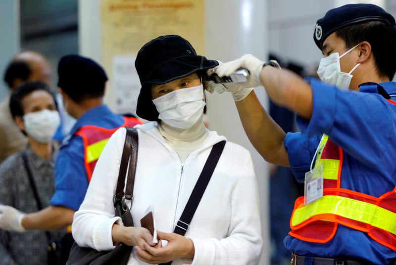 FILE PHOTO: A health worker wearing a mask to protect from the flu-like Severe Acute Respiratory Syndrome (SARS) takes a woman's temperature, after she arrived by train from Guangzhou, at Hunghom railway station, Hong Kong