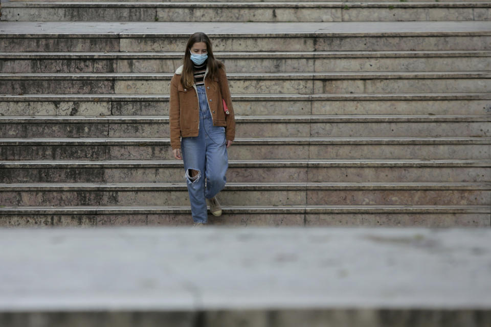 A young woman wearing a face mask enters a subway station in Lisbon, Friday, Jan. 22, 2021. Portugal's COVID-19 surge is continuing unabated, with a new record of daily deaths, hospitalizations and patients in intensive care. (AP Photo/Armando Franca)