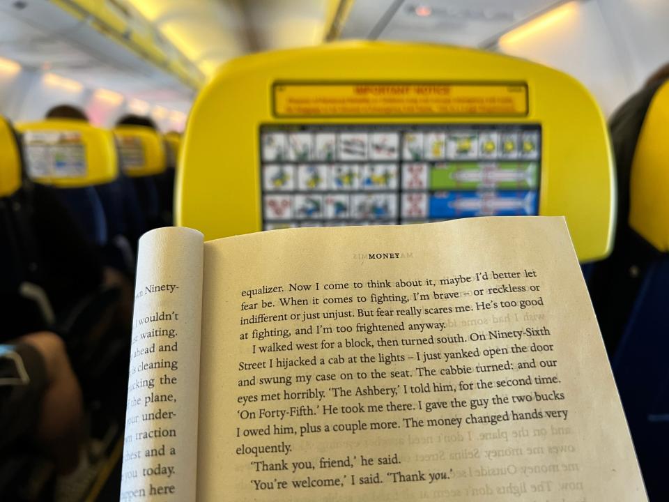 An open page of the novel "Money" by Martin Amis is displayed on a Ryanair flight.