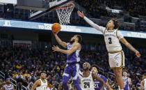 Kansas State's Markquis Nowell, center, makes a layup against Wichita State defender Craig Porter IV, right, during the first half of an NCAA college basketball game Sunday, Dec. 5, 2021, in Wichita, Kan. (Travis Heying/The Wichita Eagle via AP)