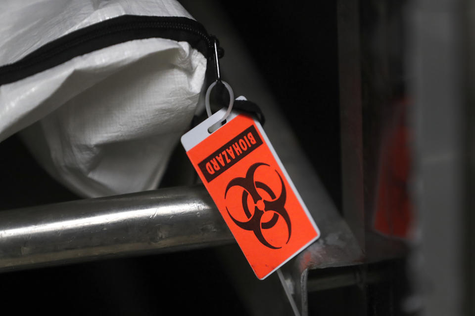 In this Tuesday, May 5, 2020, photo, an orange biohazard tag hangs from a body bag in an isolated refrigerated unit set aside for bodies infected with coronavirus at the Cook County morgue in Chicago. (AP Photo/Charles Rex Arbogast)