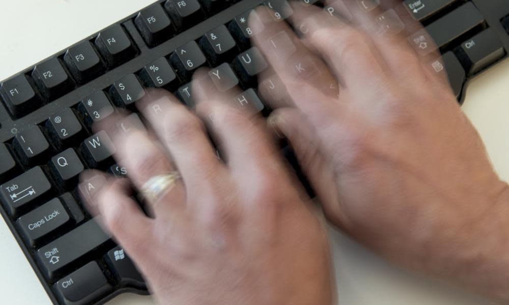 A man types on a computer keyboard.