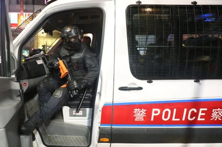 A riot police holds his weapons and wait in a police car in Hong Kong,