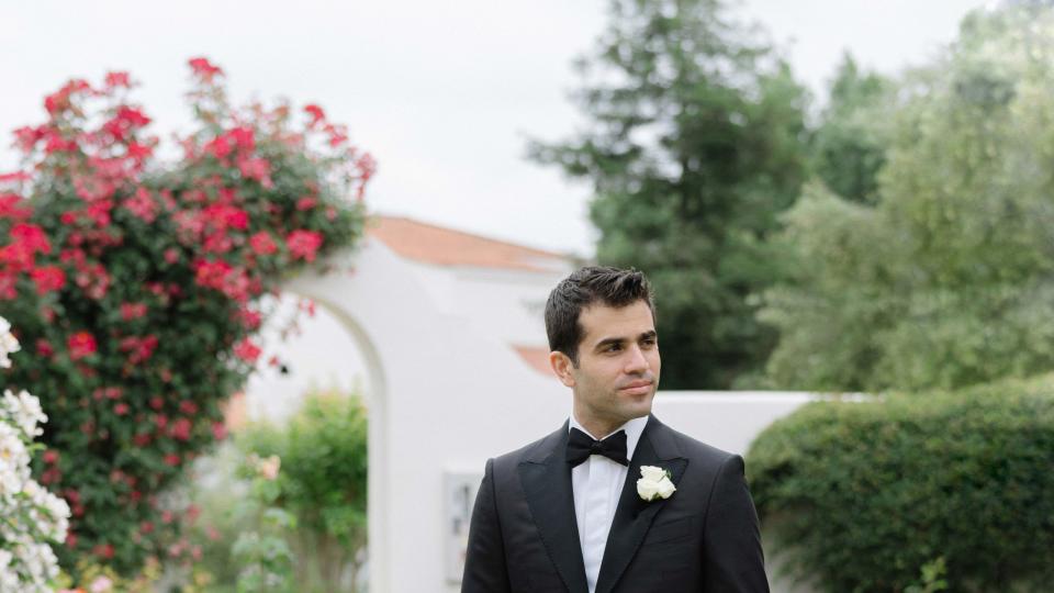 a man in a suit walking down a path in a garden