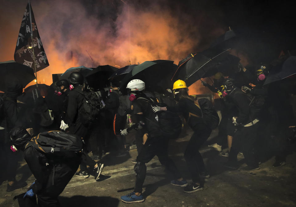 Students use umbrellas as a shields during a clash with police at the Chinese University in Hong Kong, Tuesday, Nov. 12, 2019. Police and protesters battled outside university campuses and several thousand demonstrators blocked roads as they took over a central business district at lunchtime on Tuesday in another day of protest in Hong Kong. (AP Photo/Kin Cheung)