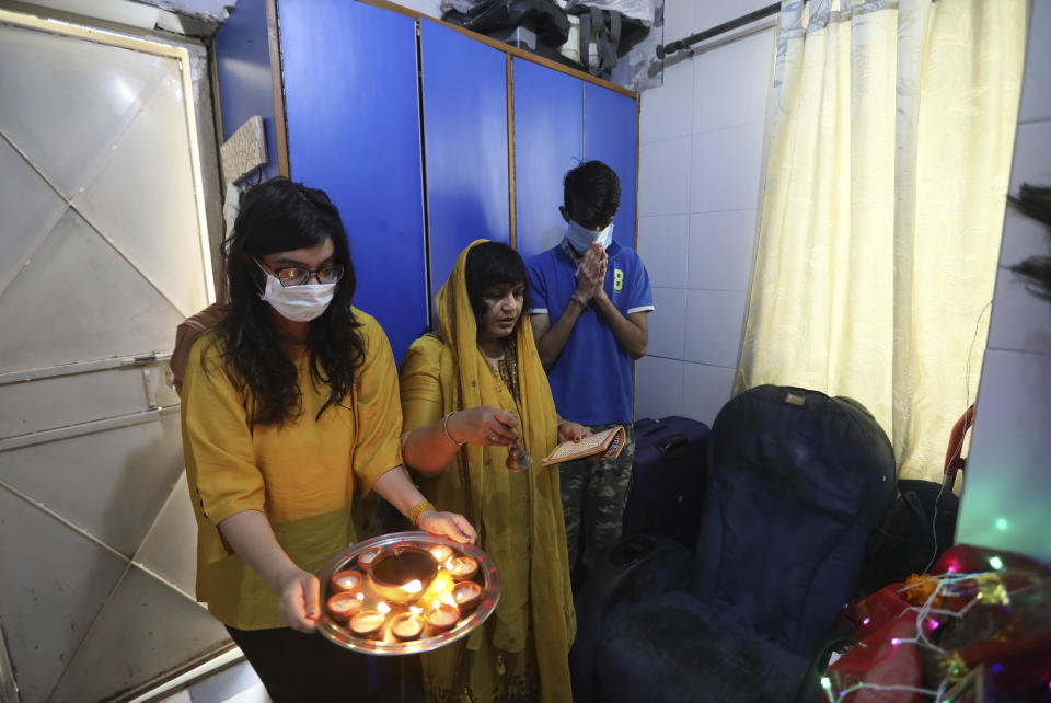 A family, wearing face masks as a precaution from coronavirus, prays inside their house on the first day of Navratri festival, where Hindu fast for nine days, in New Delhi, India, Wednesday, March 25, 2020. The world's largest democracy went under the world's biggest lockdown Wednesday, with India's 1.3 billion people ordered to stay home in a bid to stop the coronavirus pandemic from spreading and overwhelming its fragile health care system as it has done elsewhere. For most people, the new coronavirus causes mild or moderate symptoms, such as fever and cough that clear up in two to three weeks. For some, especially older adults and people with existing health problems, it can cause more severe illness, including pneumonia and death. (AP Photo/Manish Swarup)