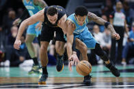 Cleveland Cavaliers guard Max Strus, left, battles Charlotte Hornets guard Tre Mann for a loose ball during the first half of an NBA basketball game in Charlotte, N.C., Wednesday, March 27, 2024. (AP Photo/Nell Redmond)