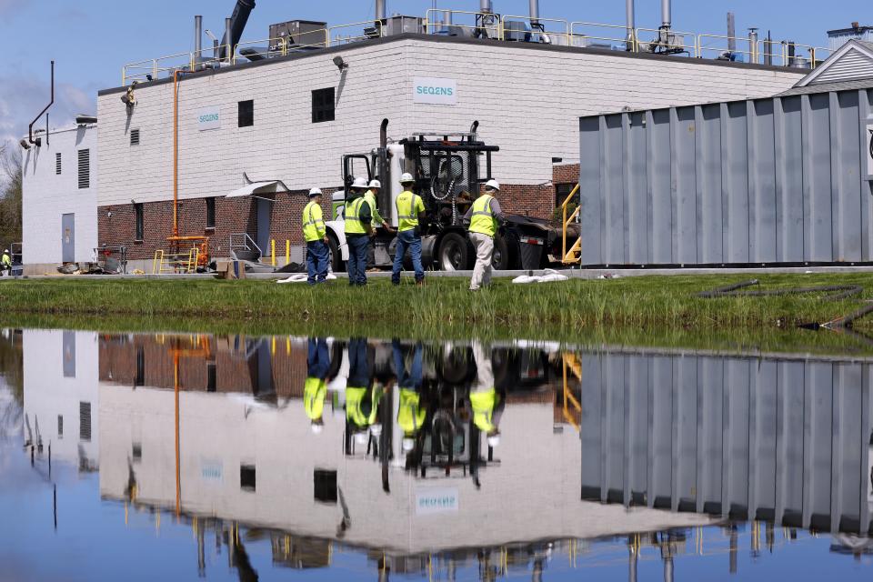 Crews work beside a small pond next to the Seqens/PCI Synthesis pharmaceutical plant, Friday, May 5, 2023, in Newburyport, Mass. The plant where a powerful blast killed a Massachusetts worker on Thursday has moved into the cleanup phase. (AP Photo/Michael Dwyer)