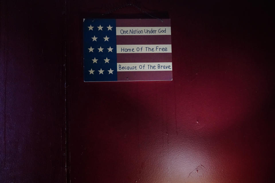 An American flag home decor sign hangs next to the door of Larry Guess' trailer home on Thursday, June 23, 2022, in Athens, Ala. Most gun violence in America is related to seemingly ordinary disputes that spin out of control and someone goes for a gun. Larry's son, David Guess, 51, was killed by gun violence in March. (AP Photo/Brynn Anderson)