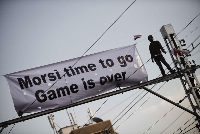 An opposition protester stands on top of a railway pole outside the Egyptian presidential palace in Cairo. On Saturday the powerful military, in its first statement since the crisis began, told both sides to talk. Otherwise, it warned, Egypt would descend "into a dark tunnel with disastrous results -- and that is something we will not allow."