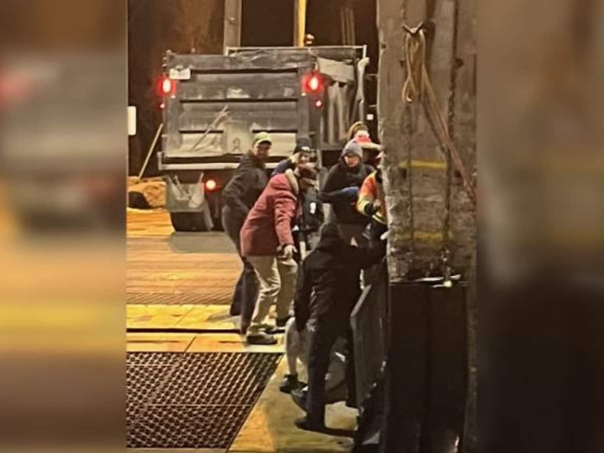 People assist a passenger who fell while disembarking the Wolfe Island Ferry at Dawson's Point Terminal on Wednesday evening. (Submitted by Dan Berry - image credit)