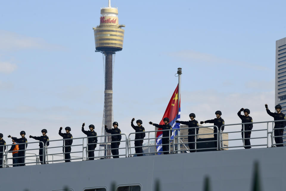 Chinese Navy personnel are seen waving onboard a Navel ship after it arrives at Garden Island. 