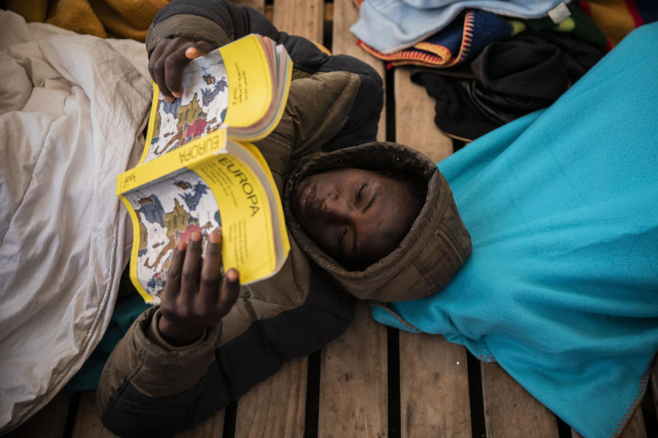 In this Sunday Jan. 12, 2020 photo, Gauro, 15, from Mali, reads a book aboard the Open Arms rescue vessel as the ship sails north with 118 people from different nationalities who were rescued on Friday off the Libyan coast. (AP Photo/Santi Palacios)