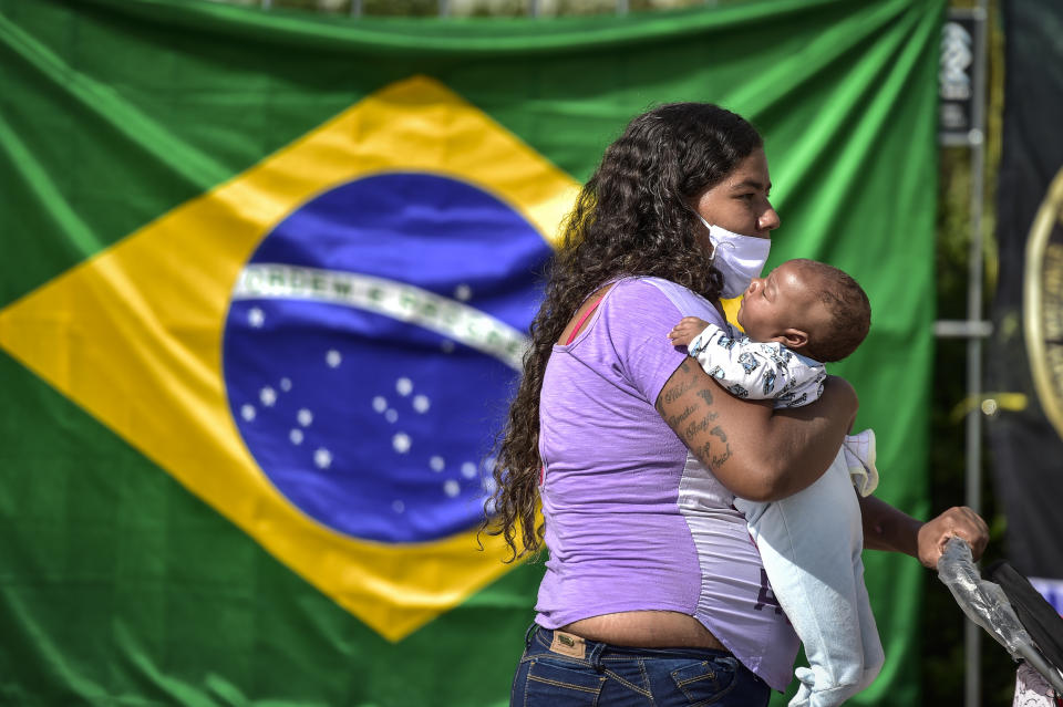 BELO HORIZONTE, BRAZIL - JUNE 05: A woman waits with hel child in line to receive lunch at Praça da Estação on June 5, 2020 in Belo Horizonte, Brazil. About 3000 meals are being distributed every Friday to poor residents, in addition to food, fruit and water. The campaign is carried out by a bank credit company in Belo Horizonte. (Photo by Pedro Vilela/Getty Images)