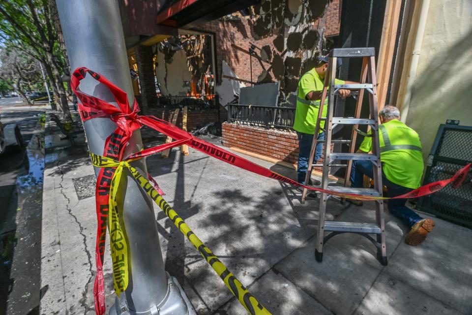 Workers begin boarding up three Downtown Visalia businesses west of the Fox Theatre that were charred by Sunday's fire.