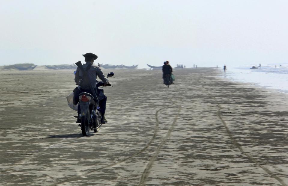 In this Jan. 16, 2017, photo, a police officer rides away with a bag of fish from the Rohingya fishermen in Maungdaw, western Rakhine state, Myanmar. Their usual, sturdy fishing boats were outlawed three months ago when Myanmar authorities launched a sweeping and violent counter-insurgency campaign in Rakhine state, home to the long-persecuted Rohingya Muslim minority. The ban on fishing boats _ meant to prevent insurgents from entering or leaving the country by sea _ is just one small provision in the wider crackdown, in which authorities have been accused of widespread abuses. (AP Photo/Esther Htusan)