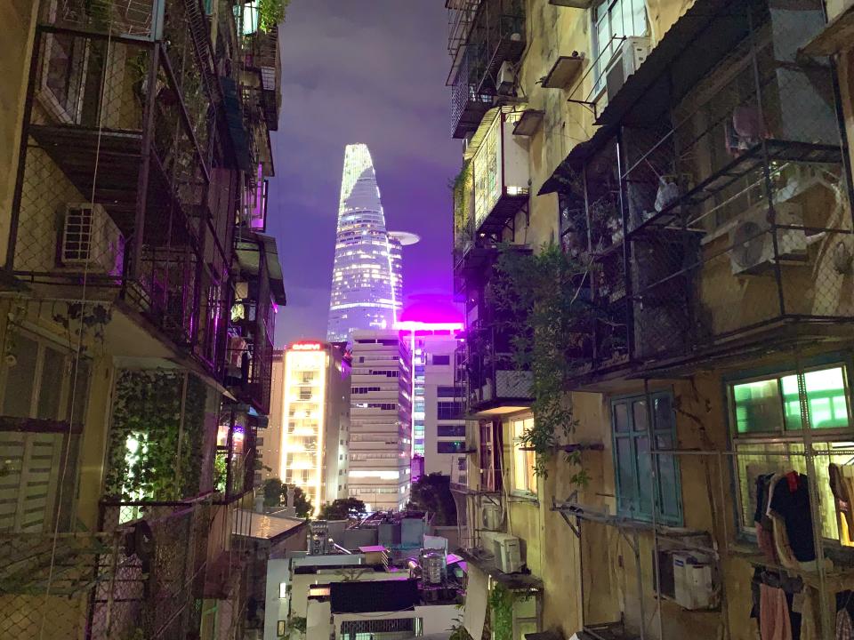 View from the hallway of a residential Vietnamese building at night showing the skyline