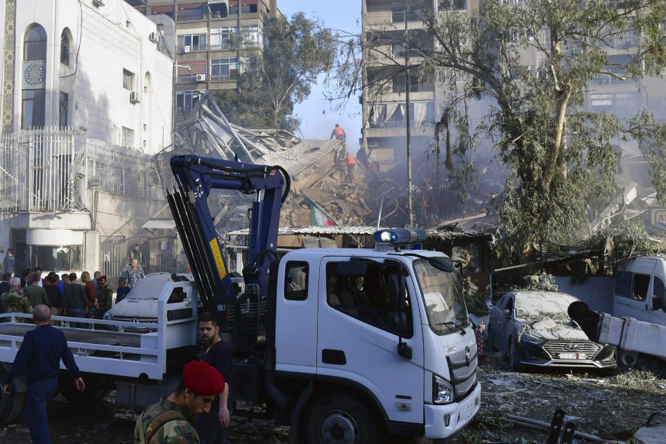 In this photo released by the official Syrian state news agency SANA, people gather near a destroyed building struck by Israeli jets in Damascus, Syria, Monday, April 1, 2024. An Israeli airstrike has destroyed the consular section of Iran's embassy in Syria, killing a senior Iranian military adviser and roughly a handful of other people, Syrian state media said Monday. (SANA via AP)