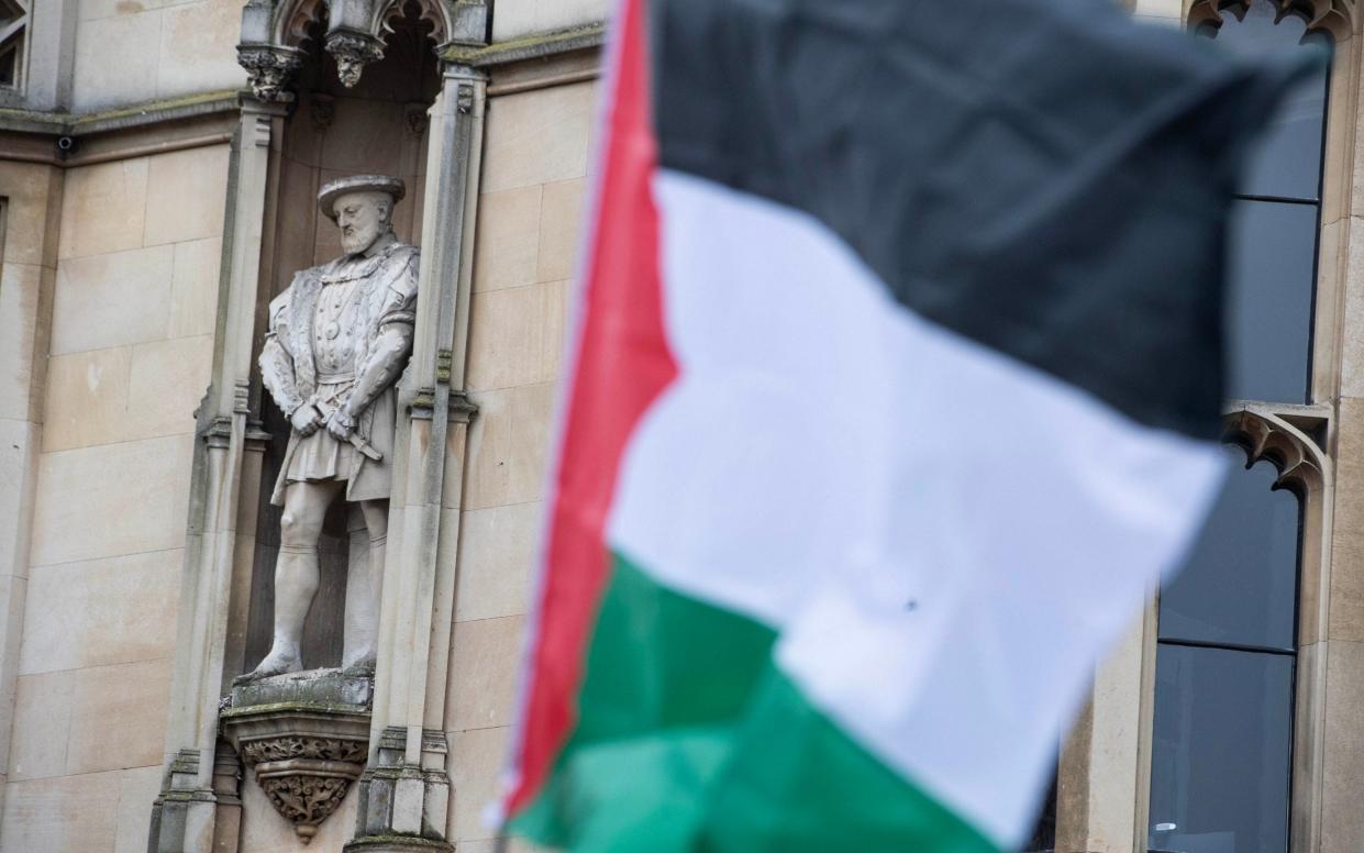 A statue of King Henry VIII on the college buildings above the Cambridge Encampment for a Free Palestine