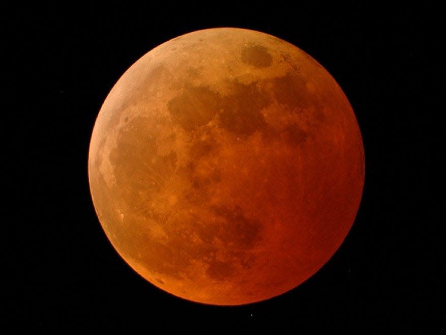 The moon appears orange-red in a total lunar eclipse on October 27, 2004.