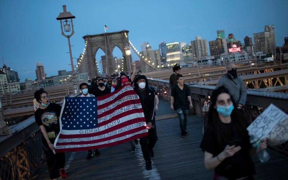 Protesters march across the Brooklyn Bridge as part of a solidarity rally calling for justice over the death of George Floyd  - AP