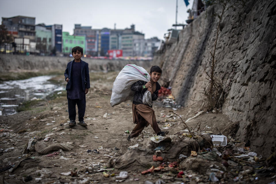 Two boys scavenge for plastic bottles, which they can sell for small amounts of money to a recycling center, on the banks of the Kabul river, November 6, 2022, in Kabul, Afghanistan / Credit: Oliver Weiken/picture alliance via Getty