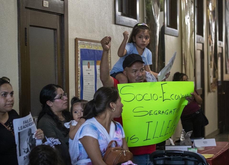 A man carries his daughter on his shoulders during a school protest.