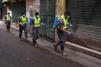 In this Friday, March 27, 2020 photo, members of the Islamic Health Society, an arm of the Iran-backed militant Hezbollah group spray disinfectant as a precaution against the coronavirus, in a southern suburb of Beirut, Lebanon. Hezbollah has mobilized the organizational might it once deployed to fight Israel or in Syria's civil war to battle the spread of the novel coronavirus. It aims to send a clear message to its Shiite supporters that it is a force to rely on in times of crisis -- particularly after it suffered a series of blows to its prestige. Opponents angrily accuse Hezbollah of helping bring the outbreak to Lebanon, saying it delayed a halt of flights from Iran for weeks after a woman who had just arrived from Iran emerged as Lebanon's first confirmed coronavirus case. (AP Photo/Bilal Hussein)