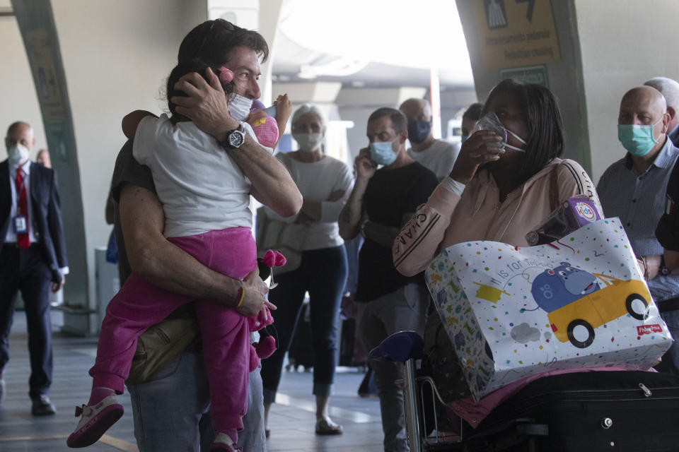 Sandro Manzato, from the Veneto region, hugs his daughter Yearline, 3, as she arrives with her mum Rubiela Perea, right, from Bogota, Colombia, at Rome's Fiumicino airport, Wednesday, June 3, 2020. Rome’s Fiumicino airport sprang back to life on Wednesday as Italy opened regional and international borders in the final phase of easing its long coronavirus lockdown, allowing families and loved ones separated by the global pandemic to finally reunite. (AP Photo/Alessandra Tarantino)