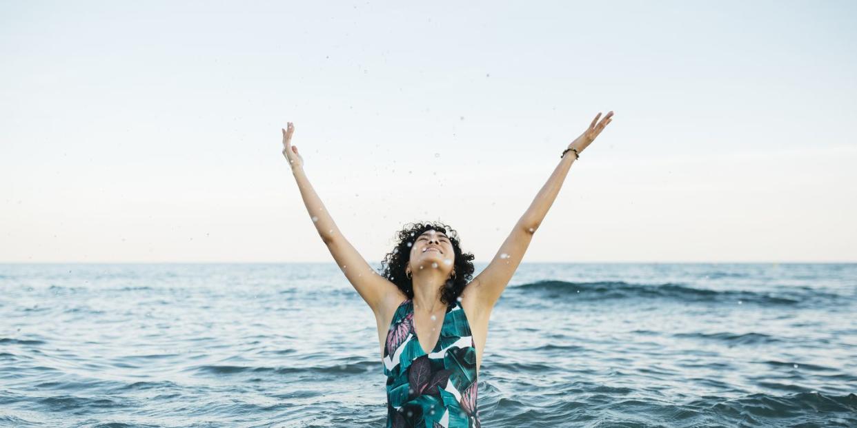 young woman wearing swimsuit in the sea splashing water to the air