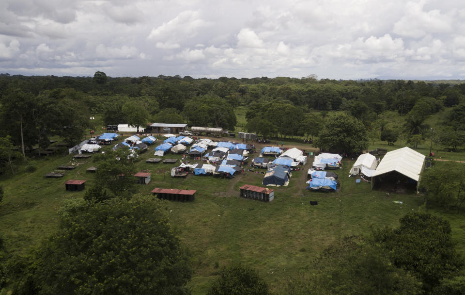 The Lajas Blancas migrant camp stands, amid the new coronavirus pandemic in Darien province, Panama, Saturday, Aug. 29, 2020. The camp is in a grassy field with tarps on wooden platforms packed tight between a dirt road and the brown waters the Chucunaque river. (AP Photo/Arnulfo Franco)