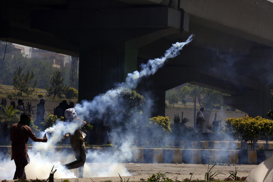 A supporter of Pakistan's former Prime Minister Imran Khan hurls back a tear gas shell toward police as he and others were protesting against the arrest of their leader, in Peshawar, Pakistan, Wednesday, May 10, 2023. Pakistan braced for more turmoil a day after Khan was dragged from court in Islamabad and his supporters clashed with police across the country. The 71-year-old opposition leader is expected in court later Wednesday for a hearing on keeping Khan in custody. (AP Photo/Muhammad Sajjad)