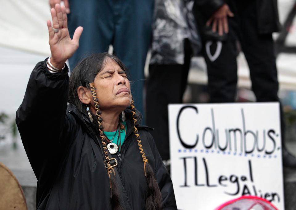 FILE - In this Monday, Oct. 10, 2011 file photo, Ferntree, of Duncan, British Columbia, a member of the Cowichan Tribes, holds her hand up as a prayer is given during a Native American protest against Columbus Day in Seattle. Protest organizers say that Columbus could not have "discovered" a western hemisphere already inhabited by about 100 million people. (AP Photo/Elaine Thompson)