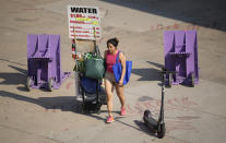 As temperatures soar above triple digits, a vendor pulls a wagon filled with water outside Coors Field during afternoon rush hour Tuesday, June 15, 2021, in Denver. (AP Photo/David Zalubowski)