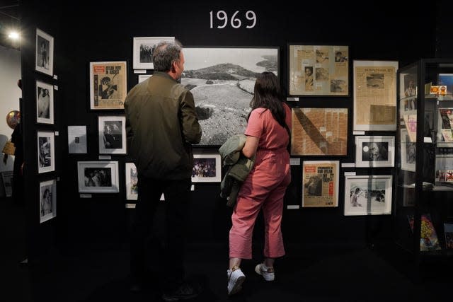 A man and woman look at framed pictures and photographs