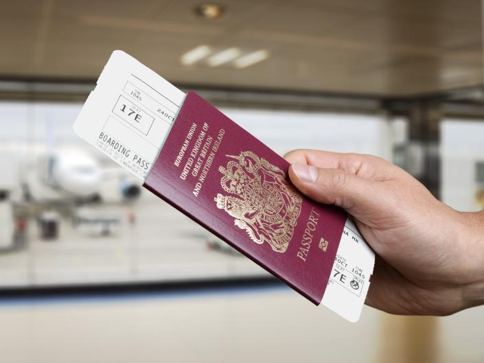 person handing over passport and plane ticket 