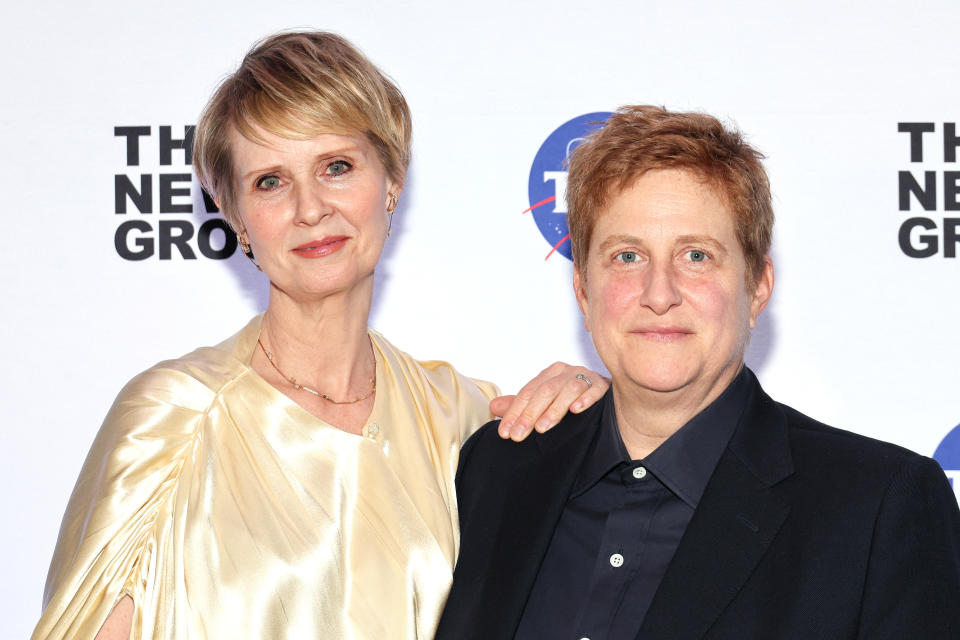 Cynthia Nixon wearing an elegant gown standing next to Christine Marinoni in a suit, both smiling at The New Group event