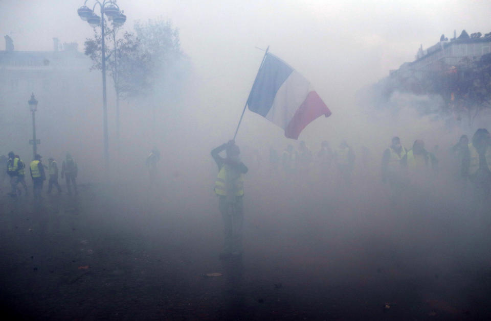 A demonstrator wearing a yellow jacket waves a French flag during a demonstration Saturday, Dec.1, 2018, in Paris. (Photo: Thibault Camus/AP)