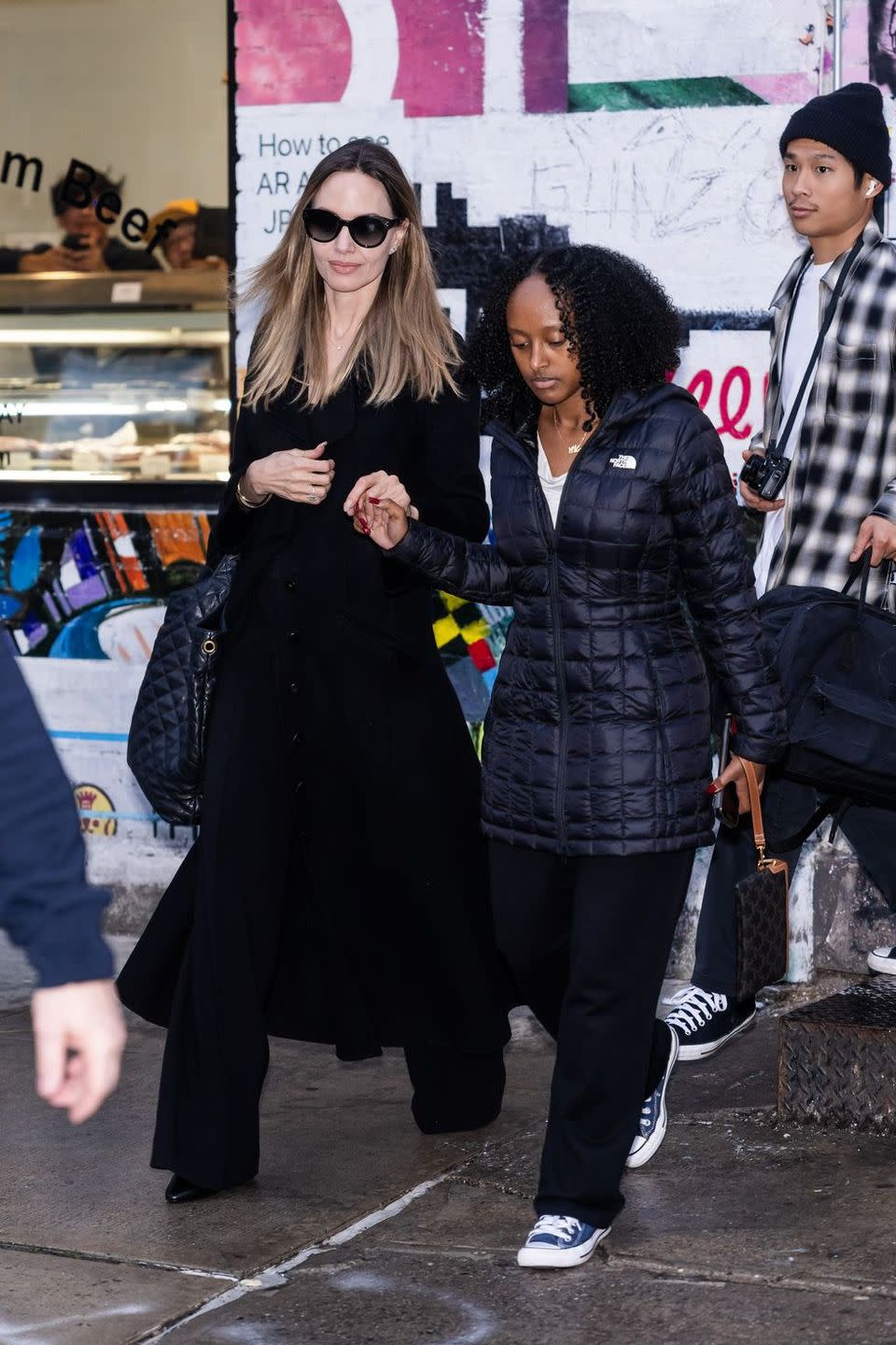 a woman in a black dress walking with a man in a black coat