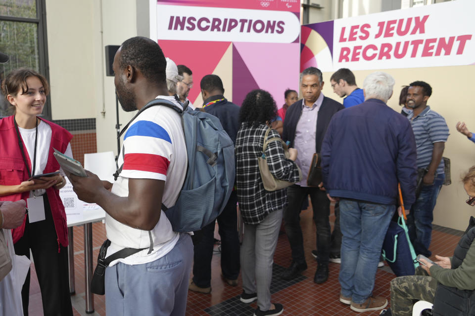 People queue for information at a job fair, Tuesday, Sept. 26, 2023 in Saint-Denis, a northern suburb of Paris. Paris Olympics organizers and their partners organized a giant job fair meant to help filling about 16,000 vacancies in key sectors including catering, security, transport and cleaning. About 50 companies are recruiting to be able to welcome next year millions of spectators and 14,500 athletes. (AP Photo/Nicolas Garriga)