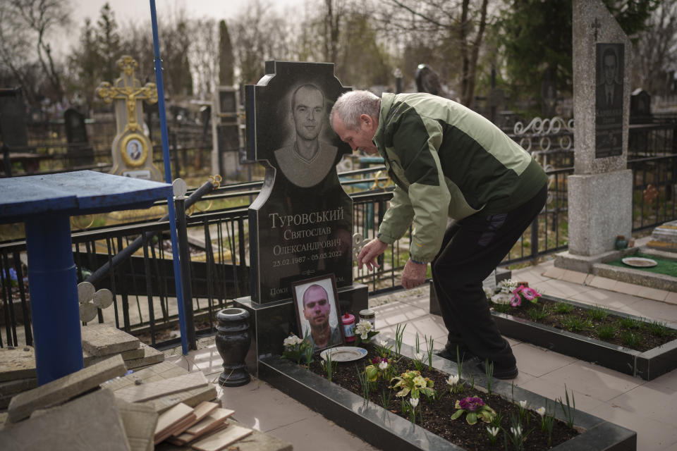 Oleksandr Turovskyi, whose 35-year old son Sviatoslav was among eight men executed in a vacant lot in the suburb of Bucha in March 2022, cares of his son's grave in Bucha, Ukraine, Saturday, March 30, 2024. Days after Russian forces withdrew from the area in late March, in the dramatic first weeks of the full-scale invasion, a photo taken by AP Photographer Vadim Ghirda revealed what happened to the eight men. "Parents should not bury their children. It's not fair," he said. (AP Photo/Vadim Ghirda)