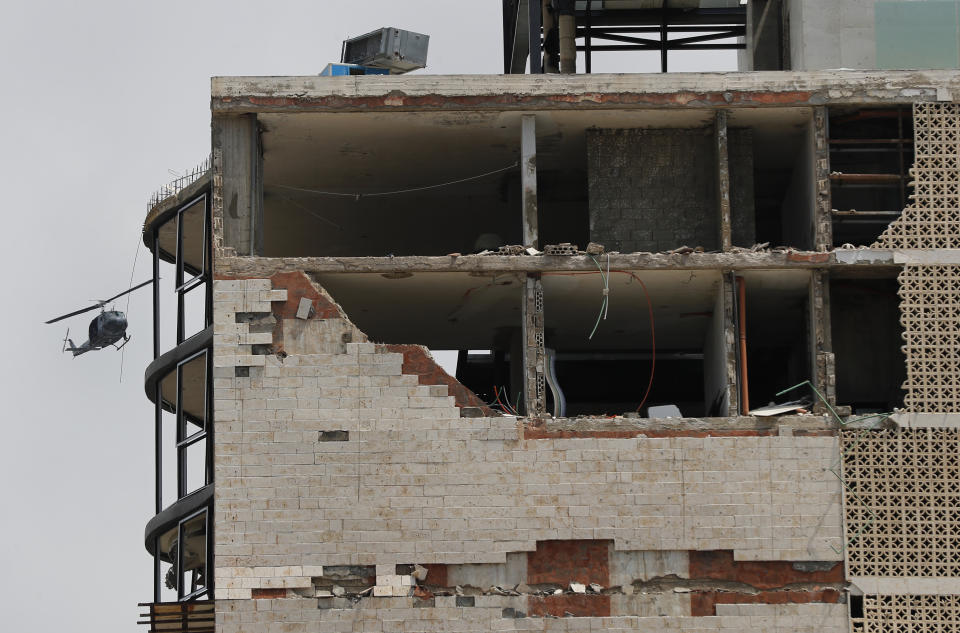 A Lebanese army helicopter flies near a damaged building, following the visit of French President Emmanuel Macron to the site of Tuesday's explosion that hit the seaport of Beirut, Lebanon, Thursday, Aug. 6, 2020. Lebanese officials targeted in the investigation of the massive blast that tore through Beirut sought to shift blame for the presence of explosives at the city's port, and the visiting French president warned Thursday that without serious reforms the country would "continue to sink." (AP Photo/Hussein Malla)