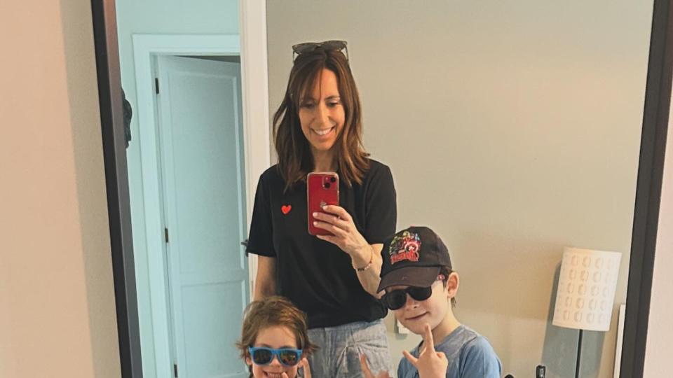 mother taking mirror selfie with three children 