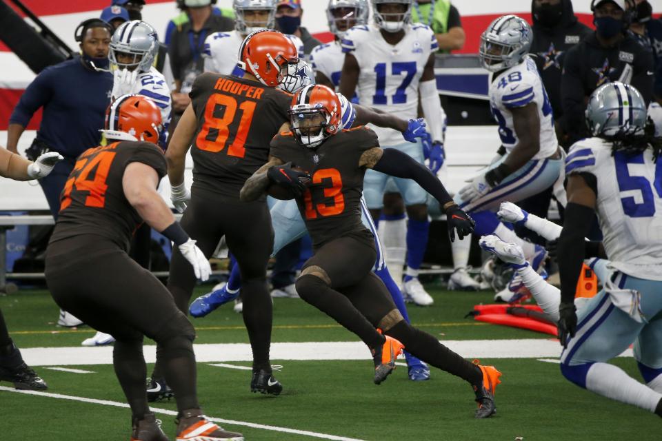 Cleveland Browns wide receiver Odell Beckham Jr. (13), makes his way through Dallas Cowboys defenders, past center JC Tretter (64) and Austin Hooper (81) on his way to the end zone for a touchdown late in the second half of an NFL football game in Arlington, Texas, Sunday, Oct. 4, 2020. (AP Photo/Michael Ainsworth)