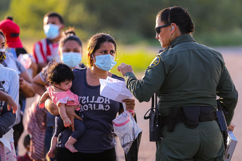 A Border Patrol agent checks paperwork  to confirm identities of migrants that crossed into the United States from Mexico southeast of La Joya, Texas on Oct. 6, 2021. Agents took in a group of over 100 migrants, 70 of which were members of families with children under the age of 6.