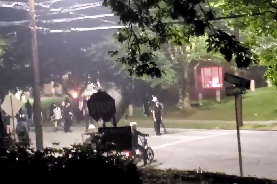 The building, seen right in the background, that houses Georgia State Patrol headquarters is vandalized in Atlanta, Sunday, July 5, 2020. Video showed protesters appearing to set off at least one firework inside the building. (Kimberly Krautter via AP)