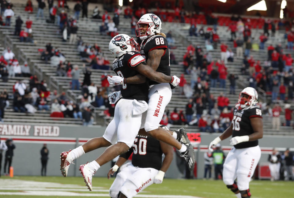 North Carolina State running back Ricky Person Jr. (8) celebrates with Devin Carter (88) after scoring on a 20-yard touchdown run against Georgia Tech during the first half of an NCAA college football game in Raleigh, N.C., Saturday, Dec. 5, 2020. (Ethan Hyman/The News & Observer via AP, Pool)