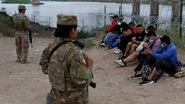 PHOTO: Migrants who had crossed the Rio Grande river into the U.S. are under custody of National Guard members as they await the arrival of U.S. Border Patrol agents in Eagle Pass, Texas, on May 20, 2022. (Dario Lopez-Mills/AP)