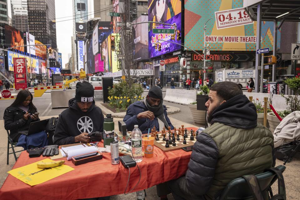 Tunde Onakoya, center, Nigerian chess champion and child education advocate, plays a chess game in Times Square, Friday, April 19, 2024, in New York. (AP Photo/Yuki Iwamura)