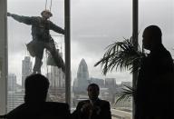 People watch as a window cleaner works outside the 14th floor at the Shard in London. REUTERS/Luke MacGregor